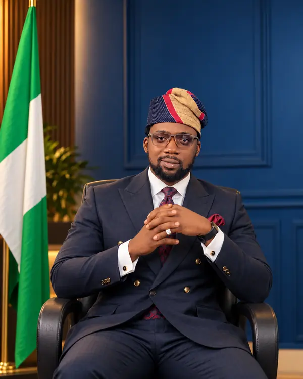 Olaseni Otusanya in a navy double-breasted suit and Yoruba cap
